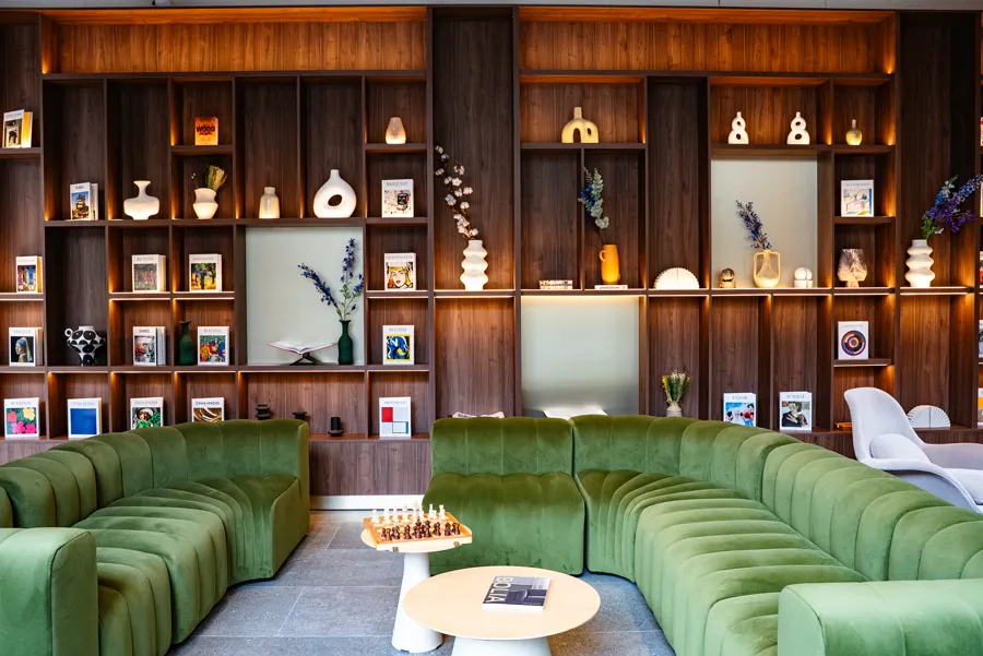 Espace lounge avec canapés en velours vert et bibliothèque design