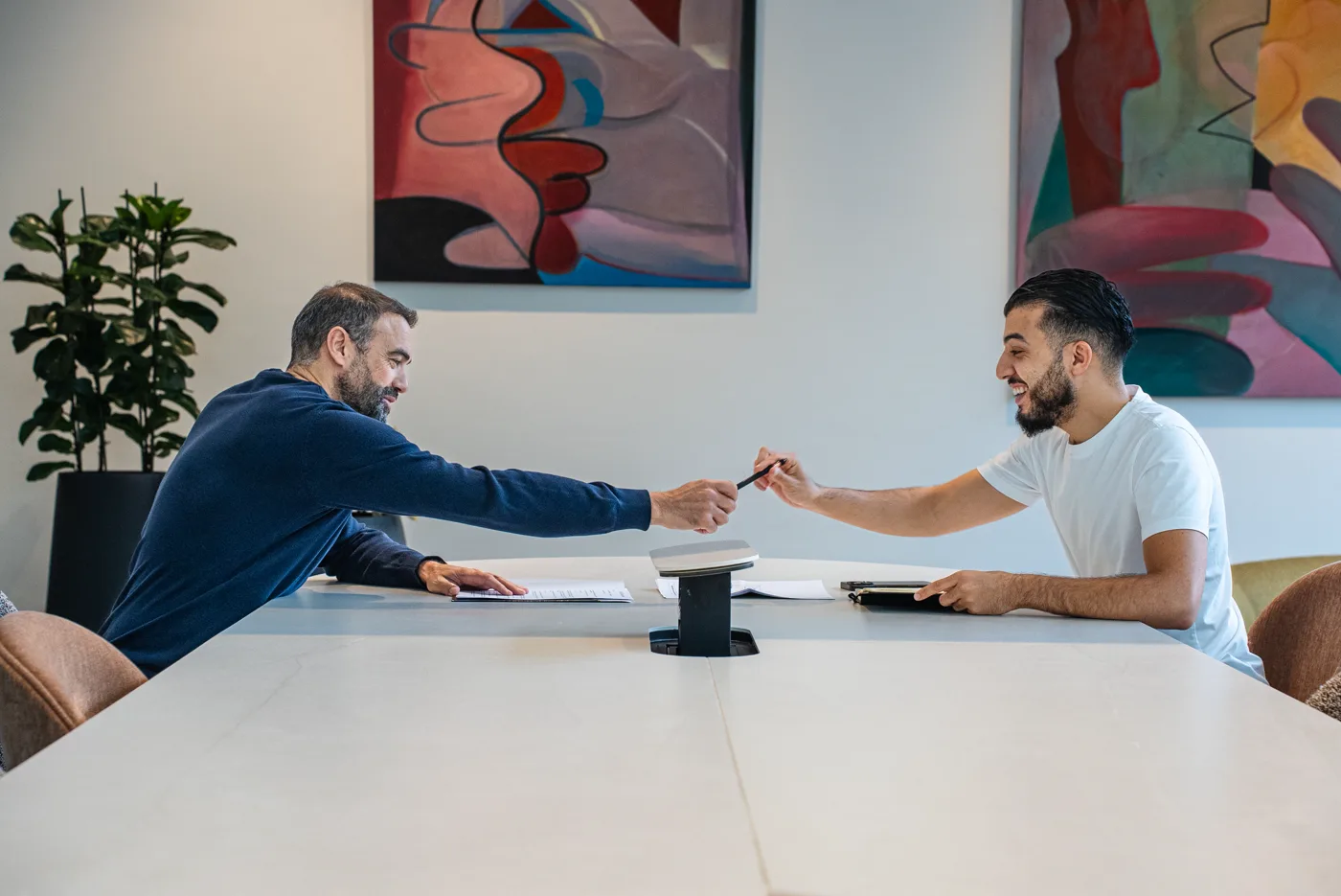 Deux personnes se serrant la main autour d'une table, un contrat signé devant elles